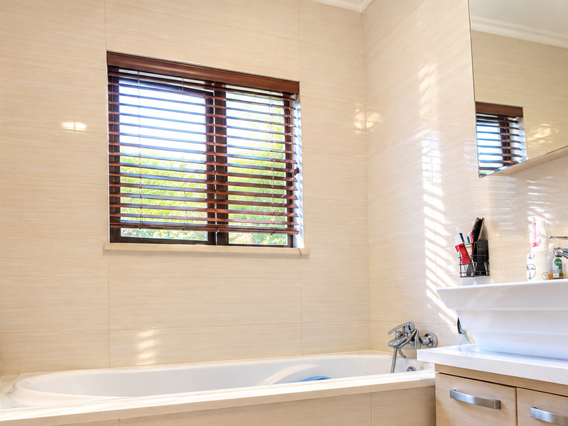 A well-maintained bathroom featuring a built-in bathtub, a modern vessel sink with vanity storage, and a wall-mounted mirror cabinet with tiled wall finishes.