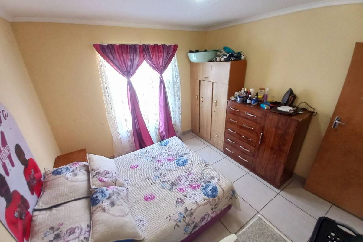 A functional bedroom featuring tiled flooring and a window that allows for natural light.