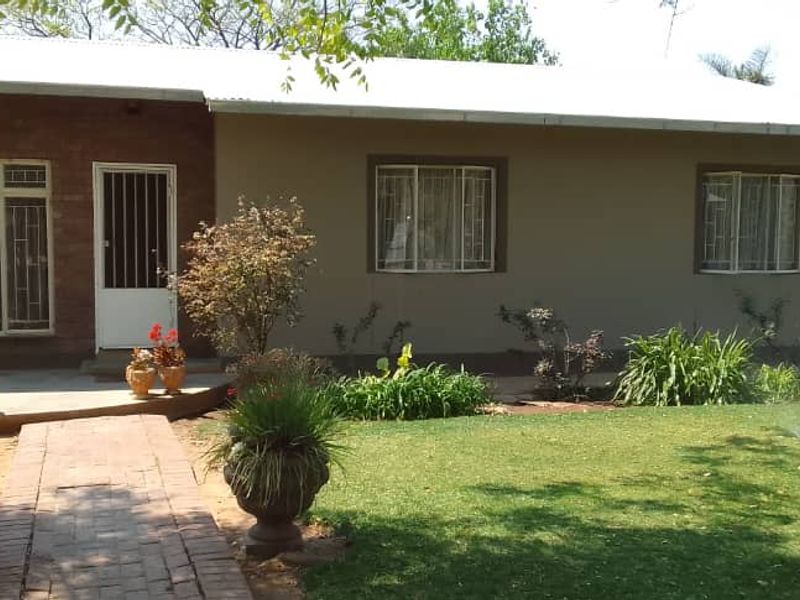 A single-story residential home featuring a brick and rendered facade, a paved walkway, and a well-maintained front garden.