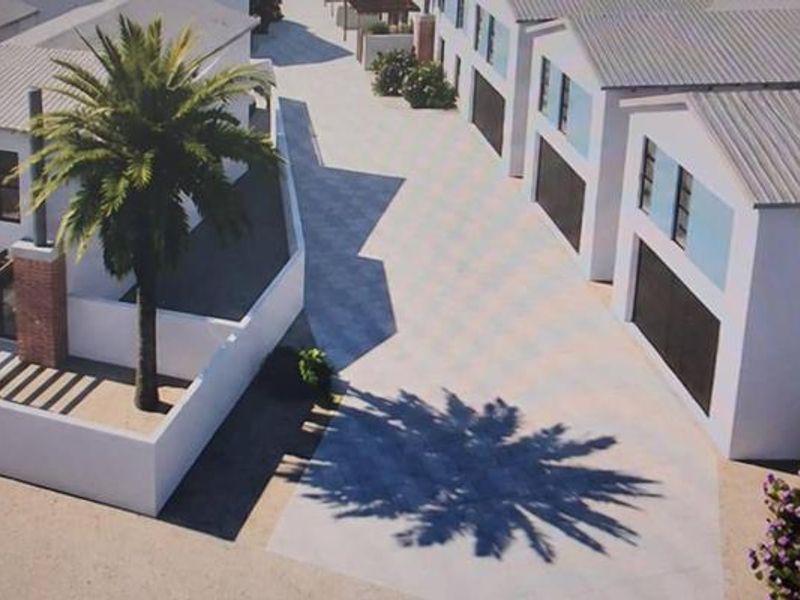 An aerial perspective of a townhouse complex featuring paved driveways, garage access, and modern architectural design with pitched roofs.