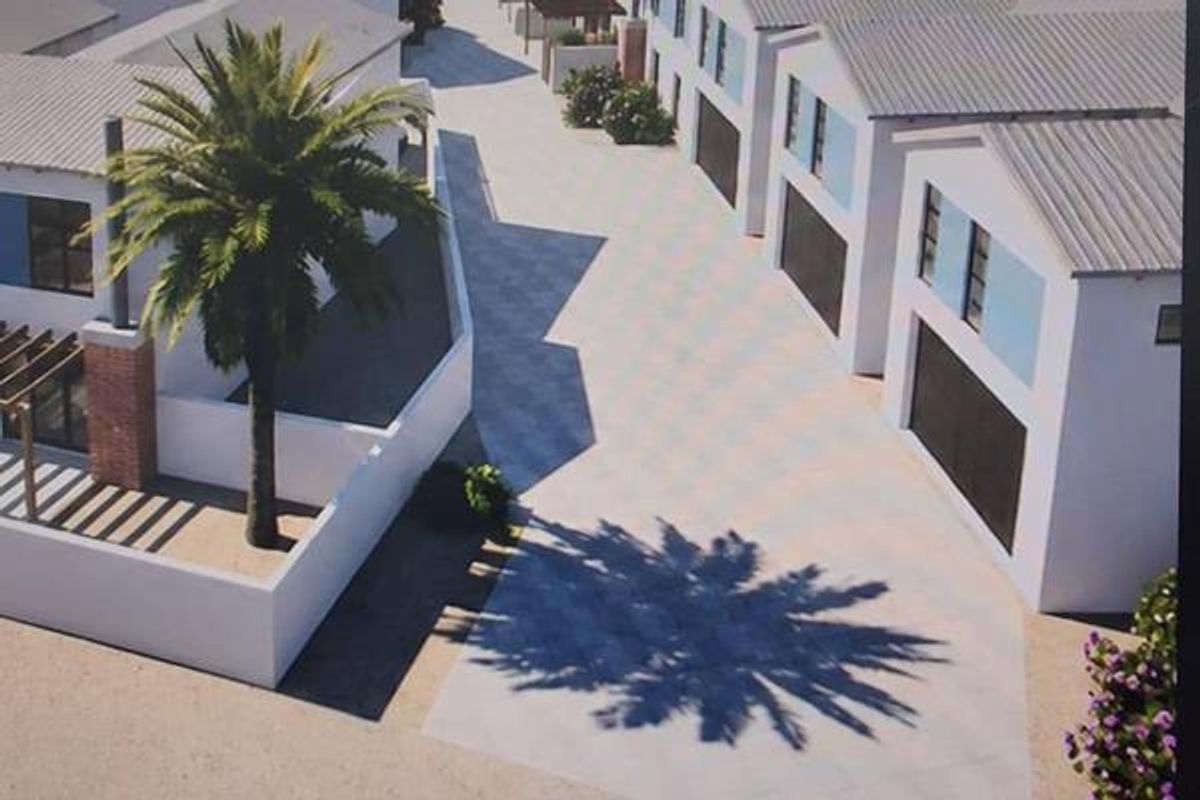 An aerial perspective of a townhouse complex featuring paved driveways, garage access, and modern architectural design with pitched roofs.