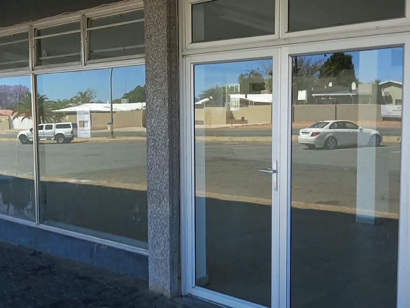 Front facade of a retail property featuring large glass display windows, aluminium frames, and a paved walkway entrance.