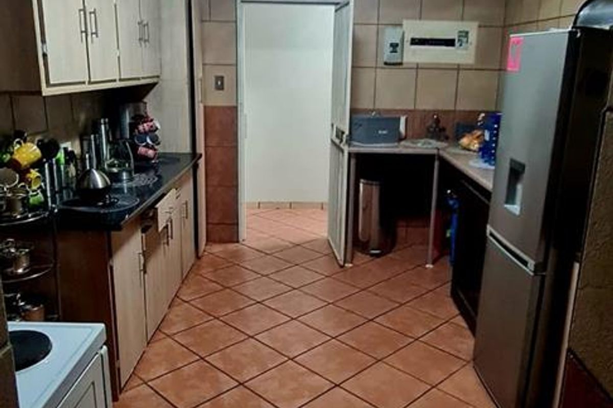 A functional kitchen featuring tiled flooring, wall-to-wall tiling, and built-in cabinetry with laminate countertops.