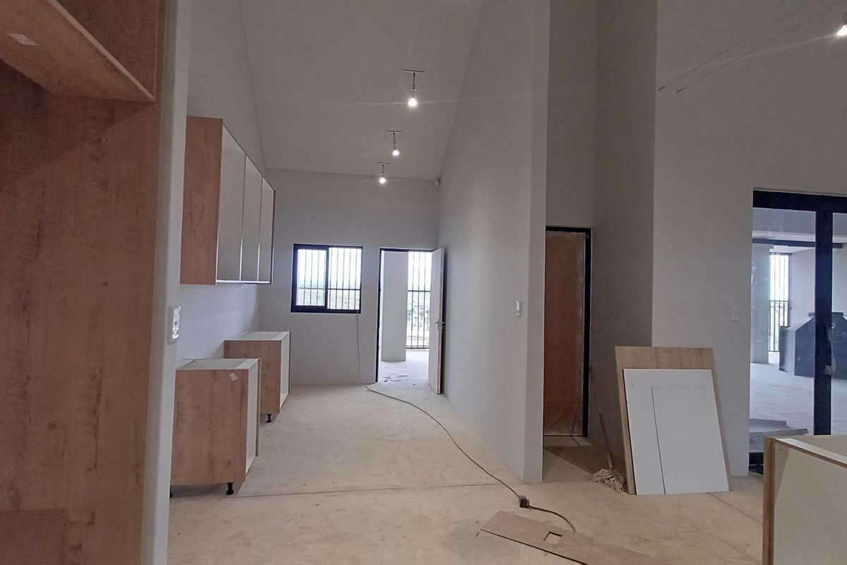 An unfinished interior space featuring light wood-finish cabinetry, recessed ceiling lighting, and large openings leading to an outdoor area.
