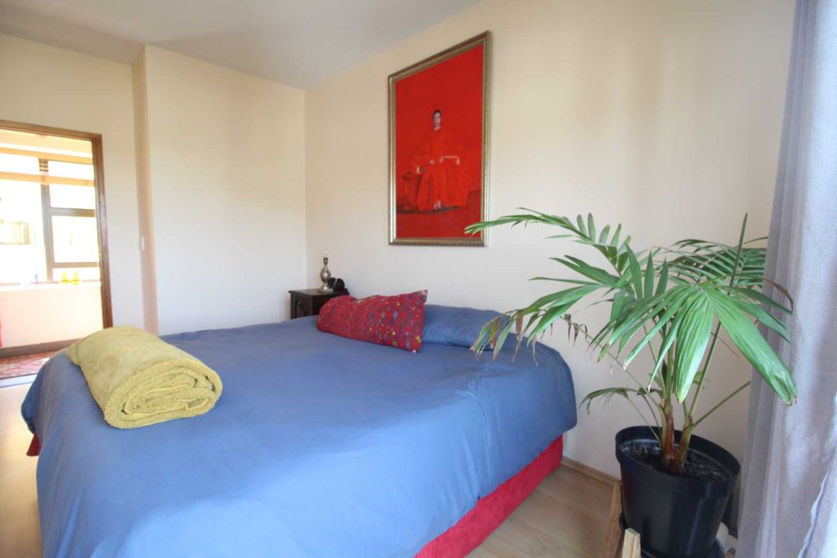 A well-lit bedroom featuring laminate flooring and a doorway leading to an adjacent space.