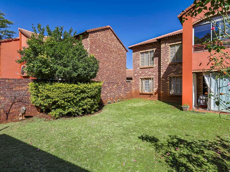 A private rear garden area featuring a well-maintained lawn, brick boundary walls, and access to the apartment's ground floor living space.