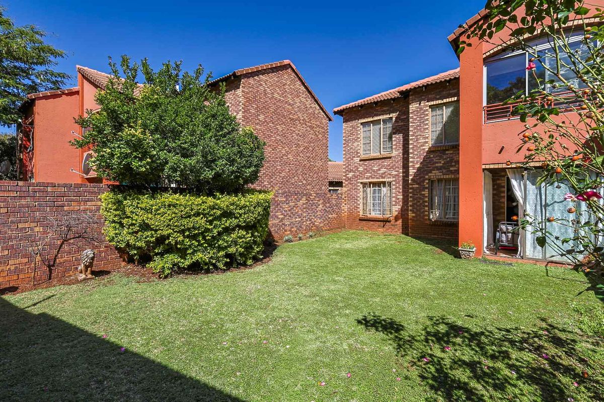 A private rear garden area featuring a well-maintained lawn, brick boundary walls, and access to the apartment's ground floor living space.