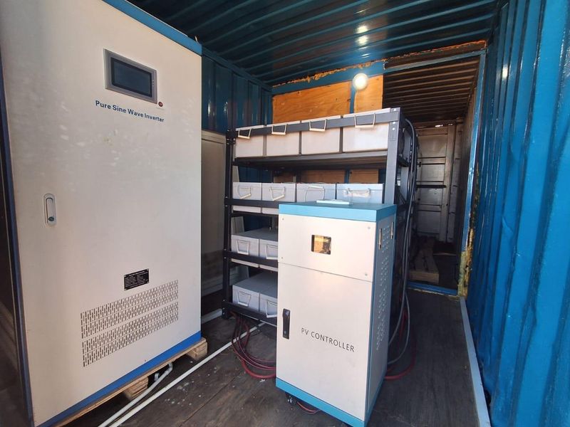 A dedicated utility space housed within a shipping container, featuring a pure sine wave inverter, PV controller, and battery storage system.
