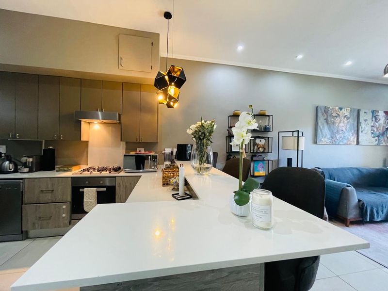 Modern open-plan kitchen featuring sleek cabinetry, stone countertops, and integrated appliances, seamlessly flowing into the adjacent living area.