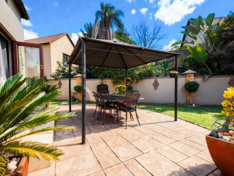 A paved outdoor patio area featuring a built-in braai and enclosed by a perimeter boundary wall, ideal for outdoor dining and entertaining.