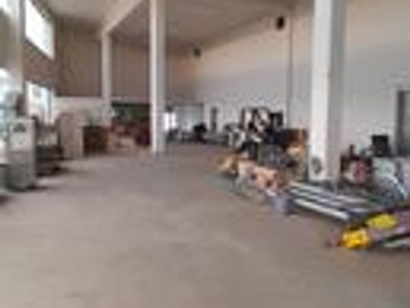 Spacious industrial utility area featuring high ceilings, structural columns, and durable concrete flooring, suitable for various commercial or storage applications.