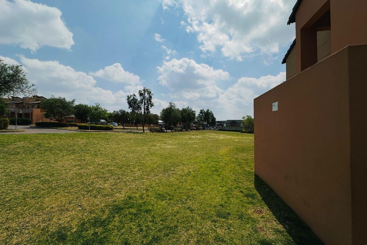 A view of the communal garden area and landscaped lawn adjacent to the apartment building exterior.