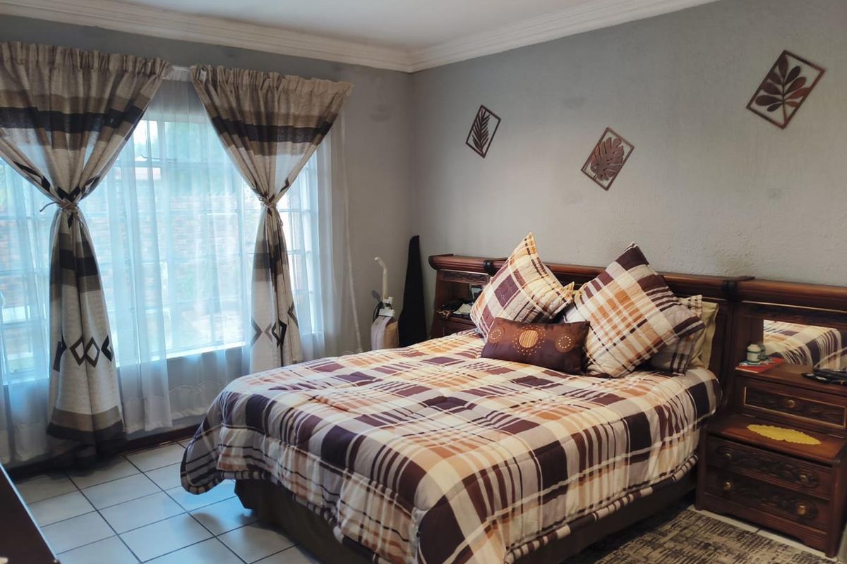 A well-lit bedroom featuring tiled flooring, crown molding, and a large window with natural light.