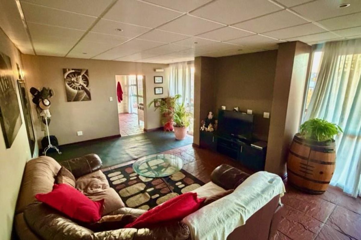 A living room featuring tiled flooring, a drop ceiling with recessed lighting, and sliding glass doors providing access to the exterior.