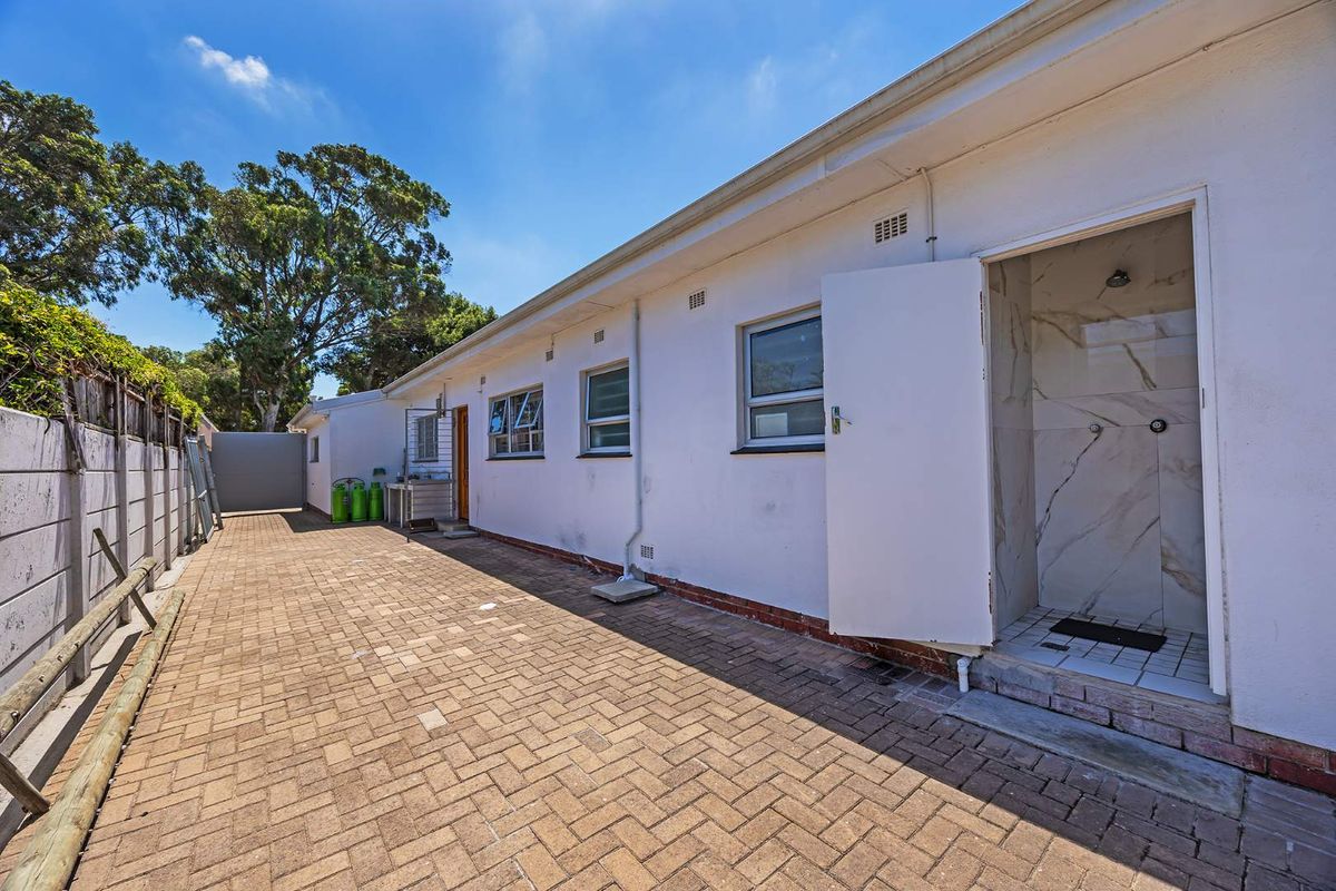 Exterior rear view showing a paved courtyard area with an outdoor shower facility and access to the property.