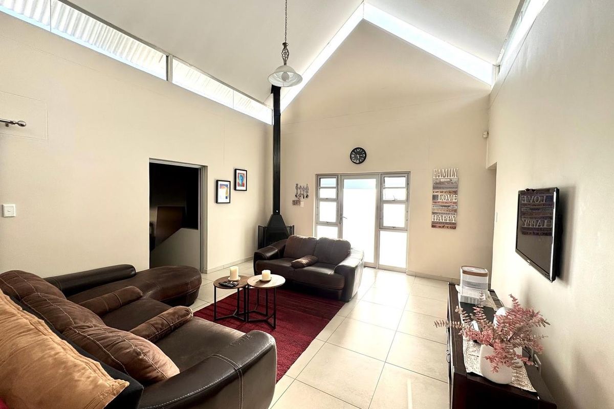 Spacious living room featuring a high vaulted ceiling with clerestory windows, tiled flooring, and a modern freestanding fireplace.