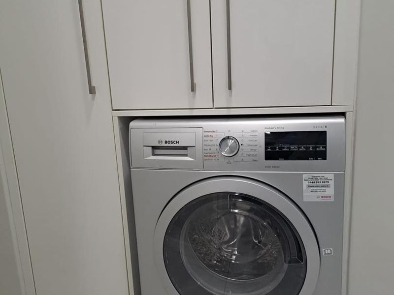 A clean and functional laundry area featuring built-in cabinetry and an integrated Bosch washing machine.