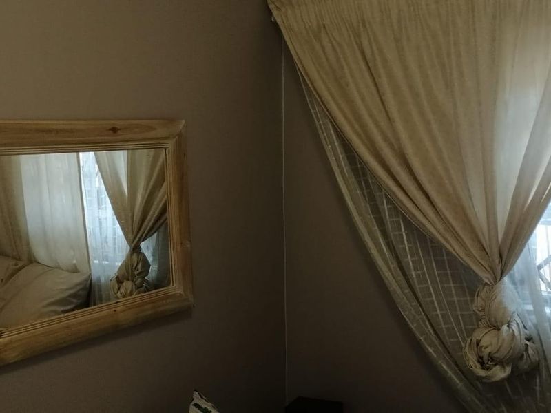 A bedroom interior featuring a window with security gate and neutral wall tones.