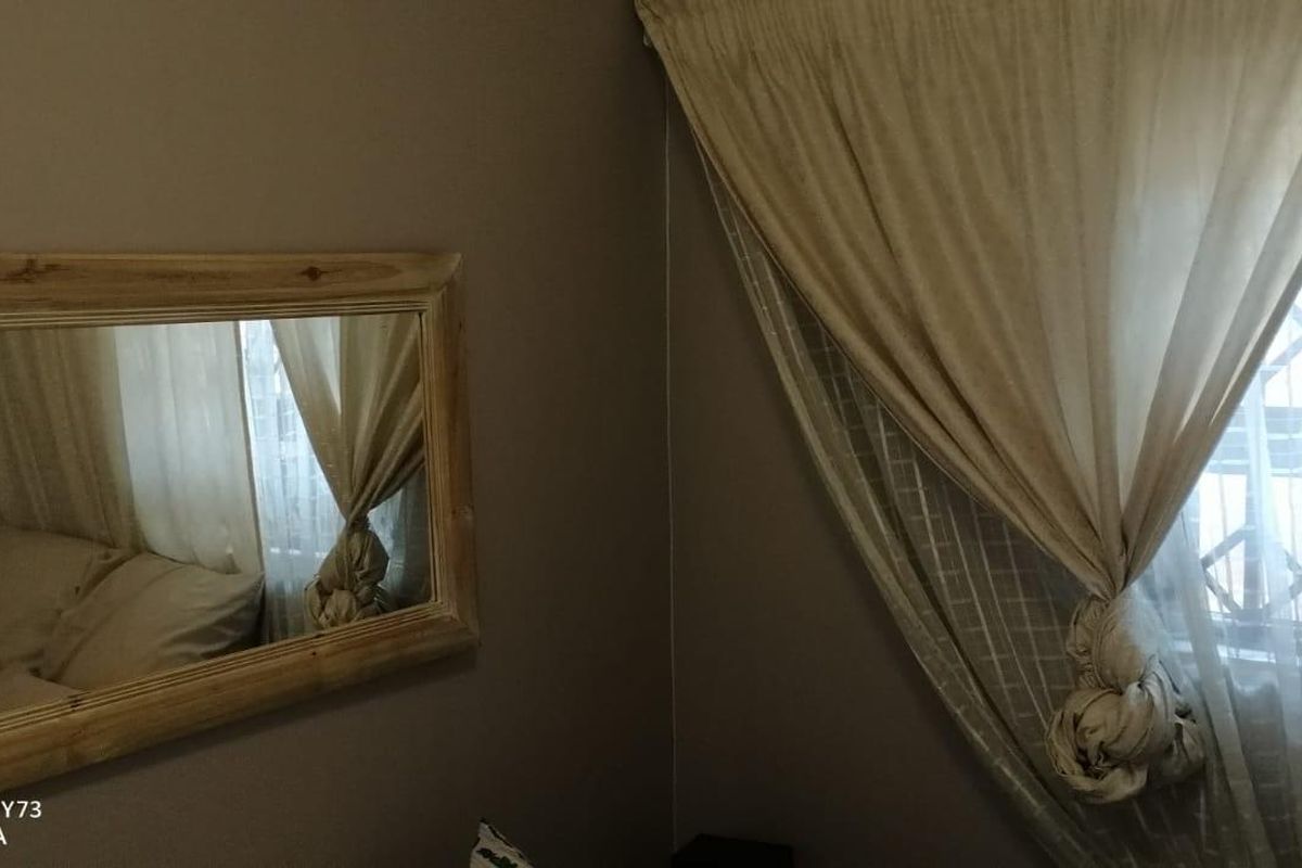 A bedroom interior featuring a window with security gate and neutral wall tones.