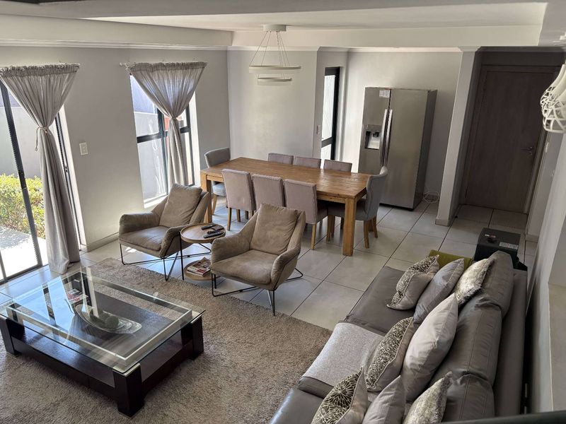 Spacious open-plan living and dining area featuring large sliding glass doors, neutral tiled flooring, and contemporary lighting fixtures.