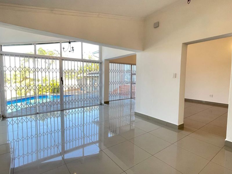 Spacious open-plan living area featuring polished tiled floors, high ceilings, and large sliding glass doors providing direct access to the pool area.