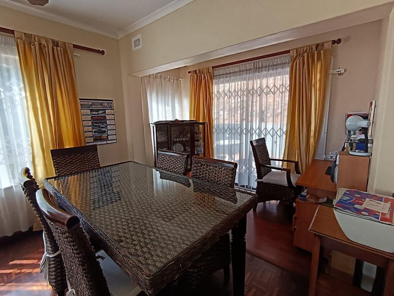 A dining room featuring parquet flooring, cove cornicing, and a sliding glass door with a security gate leading to the exterior.
