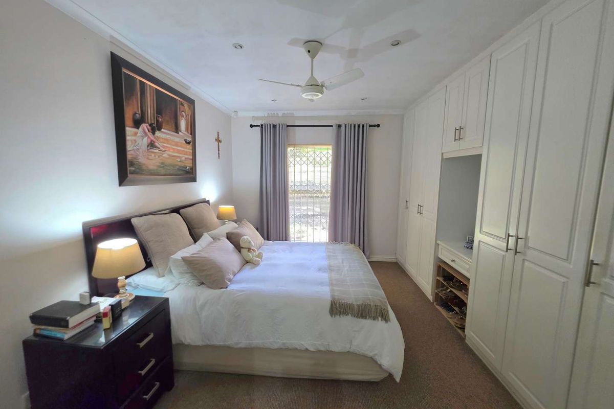 A well-maintained bedroom featuring extensive built-in cabinetry, a ceiling fan, and carpeted flooring, providing ample storage and a comfortable living space.