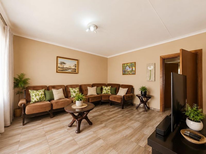 A well-maintained living room featuring neutral wall tones, tiled flooring, and classic cove cornicing, providing a comfortable and functional space.