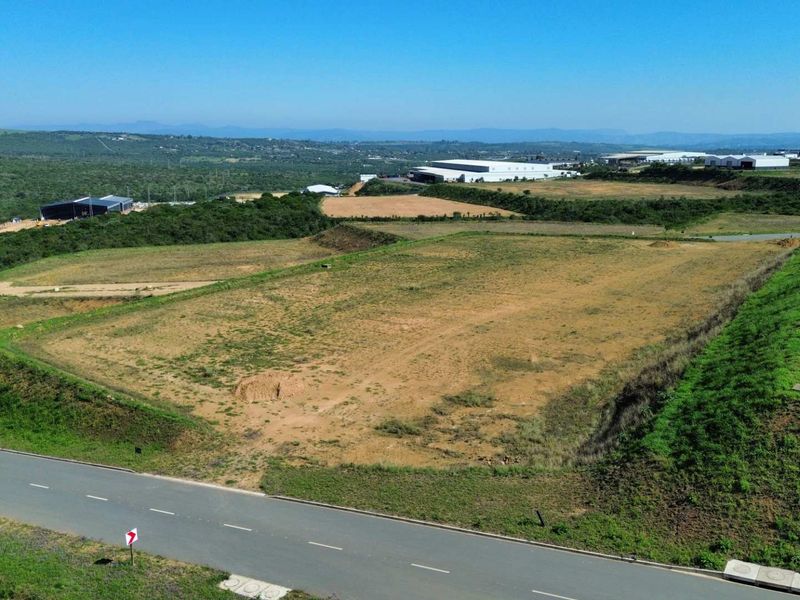Aerial view of a cleared industrial development plot with direct access to a paved road, situated in a developing industrial estate.