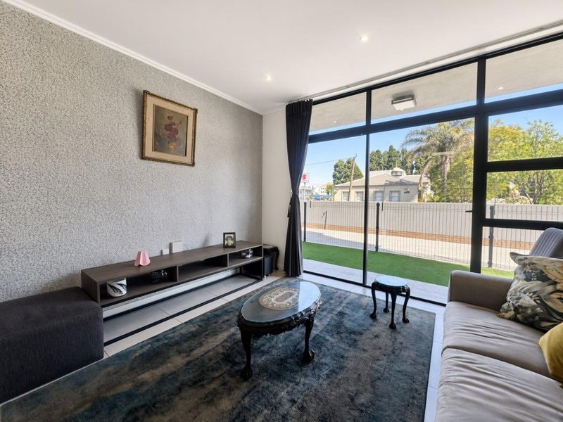 A bright living room featuring large sliding glass doors that provide natural light and access to an outdoor area, complemented by modern tiled flooring.