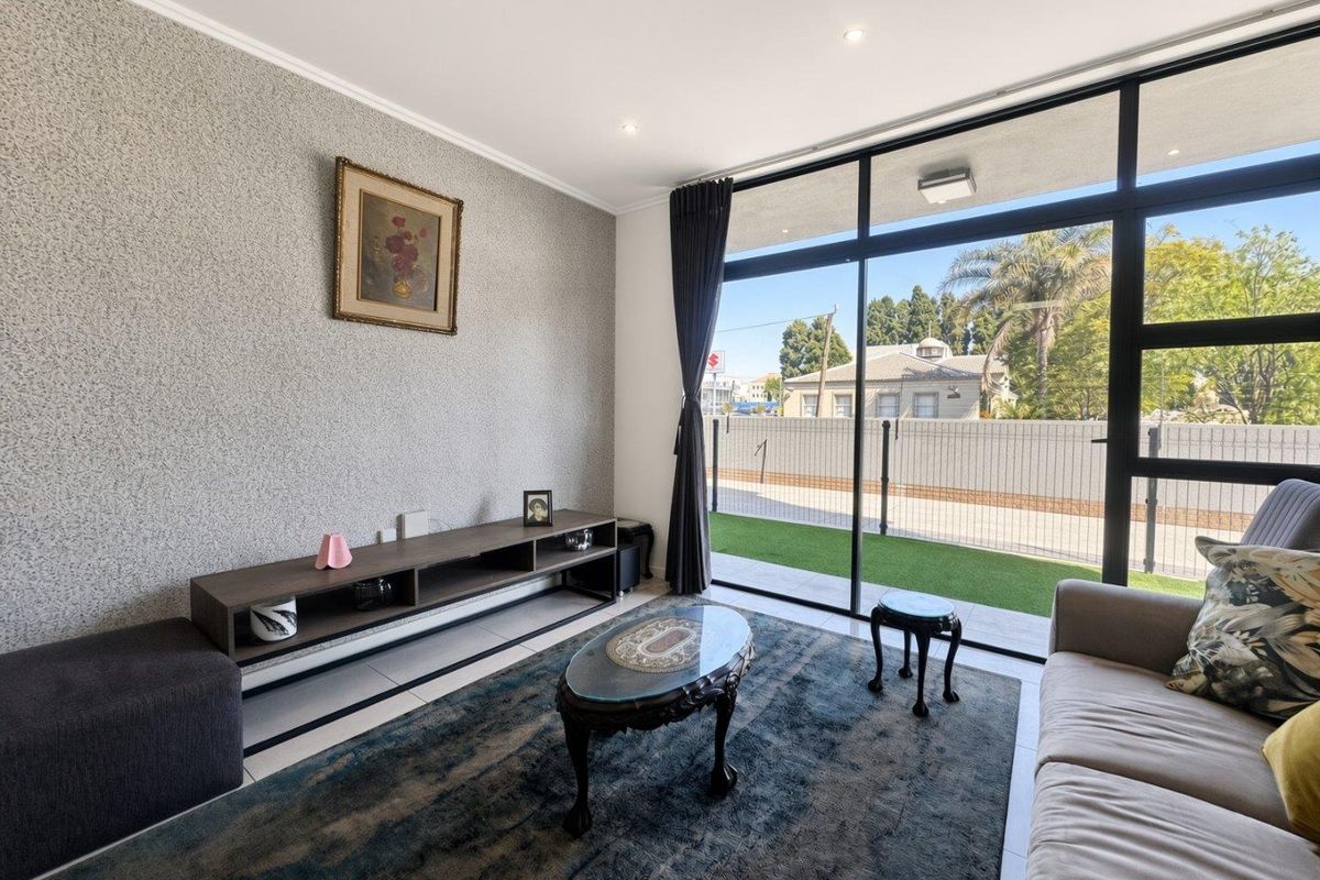 A bright living room featuring large sliding glass doors that provide natural light and access to an outdoor area, complemented by modern tiled flooring.