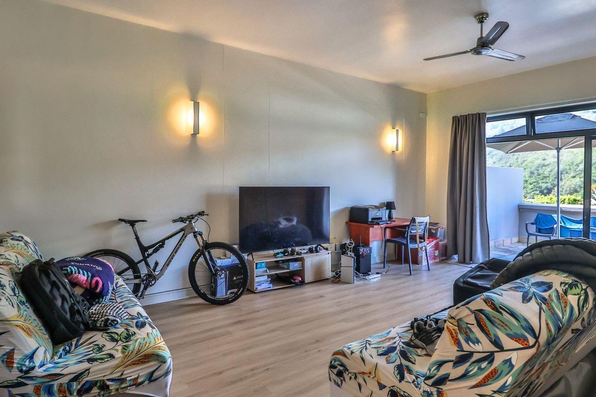 Spacious living room featuring light wood-look flooring, wall-mounted lighting fixtures, and direct access to an outdoor balcony area.