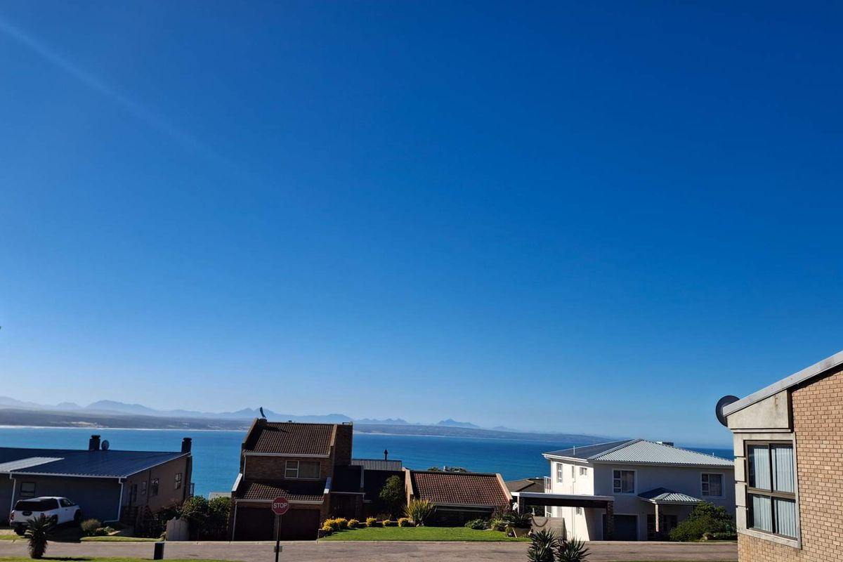 A scenic elevated view overlooking the surrounding residential neighborhood with a clear outlook towards the ocean and distant mountain range.