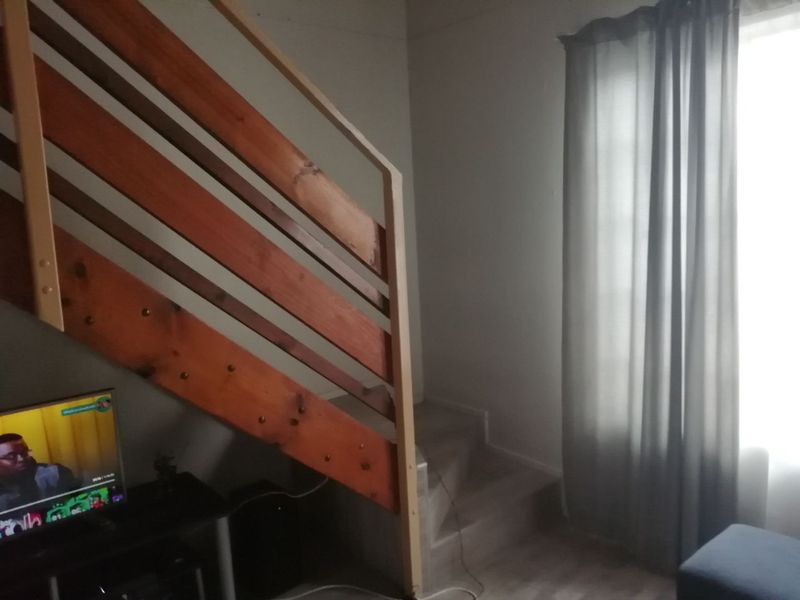 A living area featuring a wooden staircase with a built-in railing, providing access to an upper level.