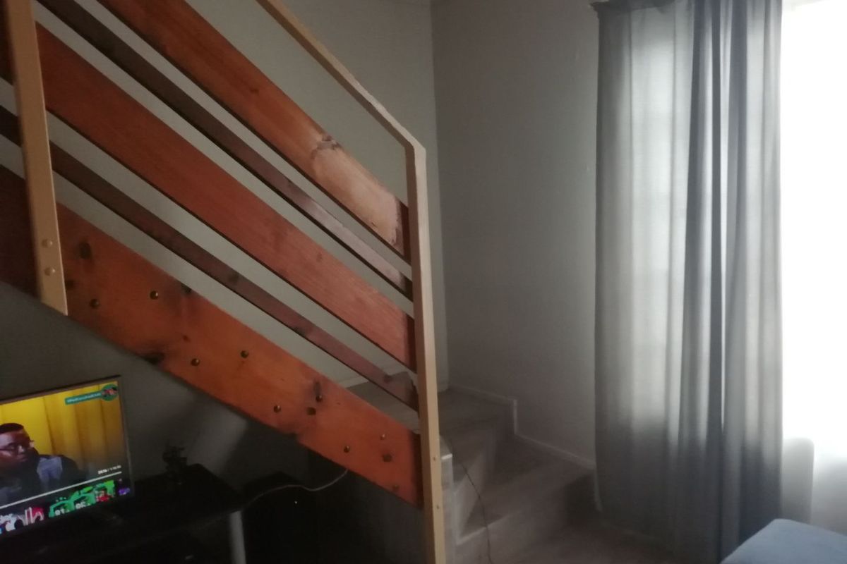 A living area featuring a wooden staircase with a built-in railing, providing access to an upper level.