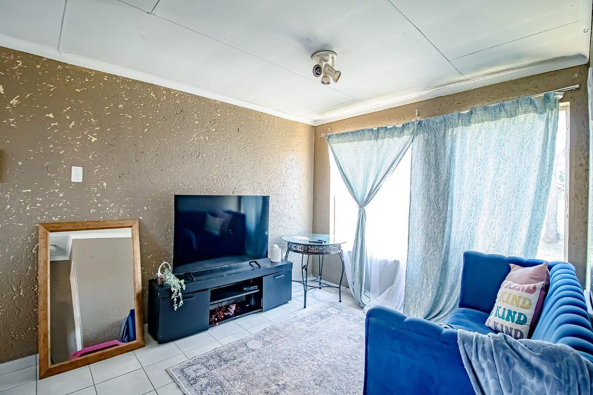 A living room featuring tiled flooring and a textured wall finish, offering a functional space with potential for cosmetic updates.