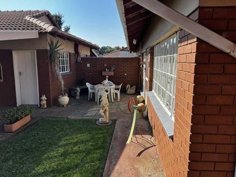A private rear courtyard featuring paved flooring, a small lawn area, and classic brick exterior walls, providing a quiet outdoor space.