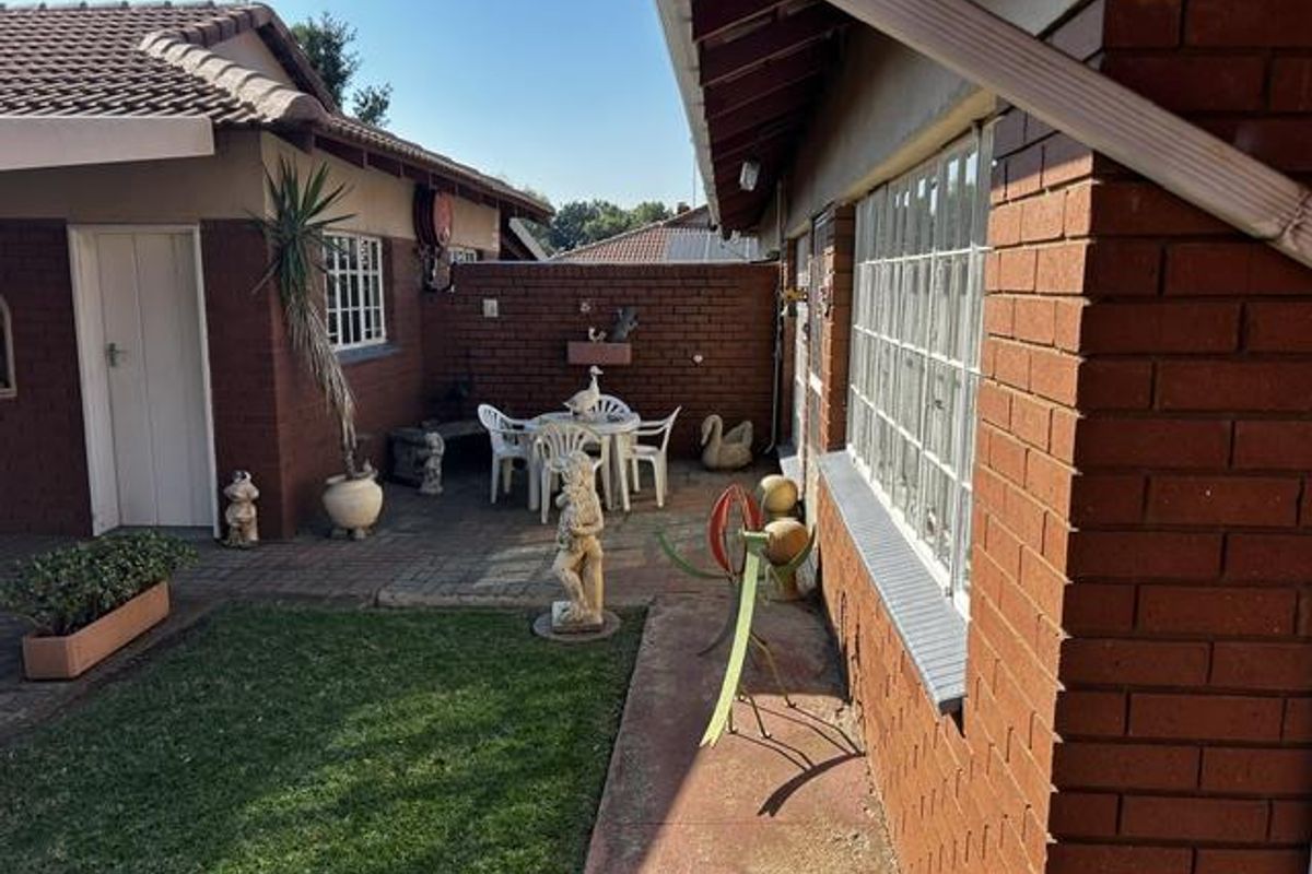 A private rear courtyard featuring paved flooring, a small lawn area, and classic brick exterior walls, providing a quiet outdoor space.