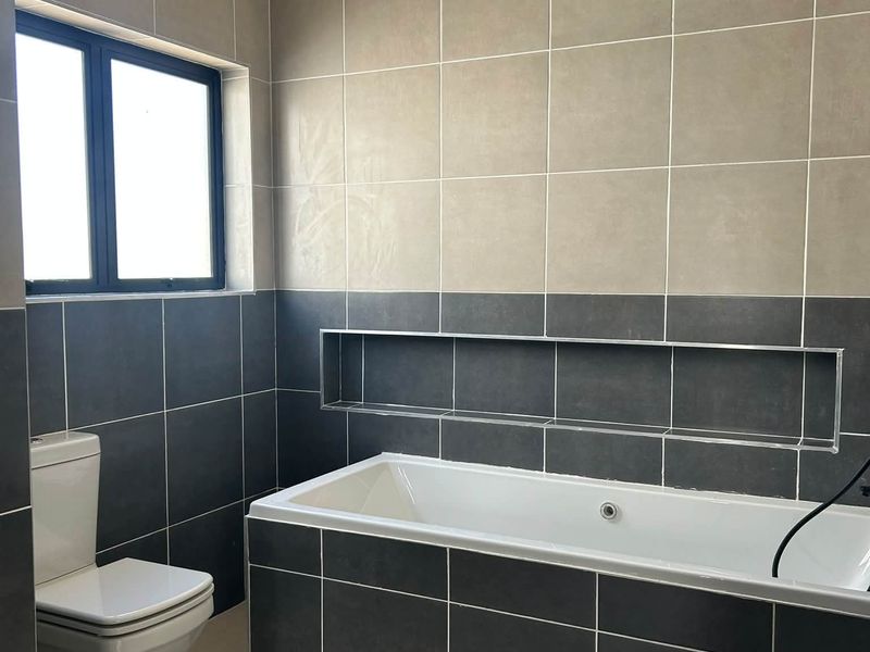 Modern bathroom featuring a built-in bathtub, a recessed wall niche for storage, and contemporary two-tone tiled walls and flooring.