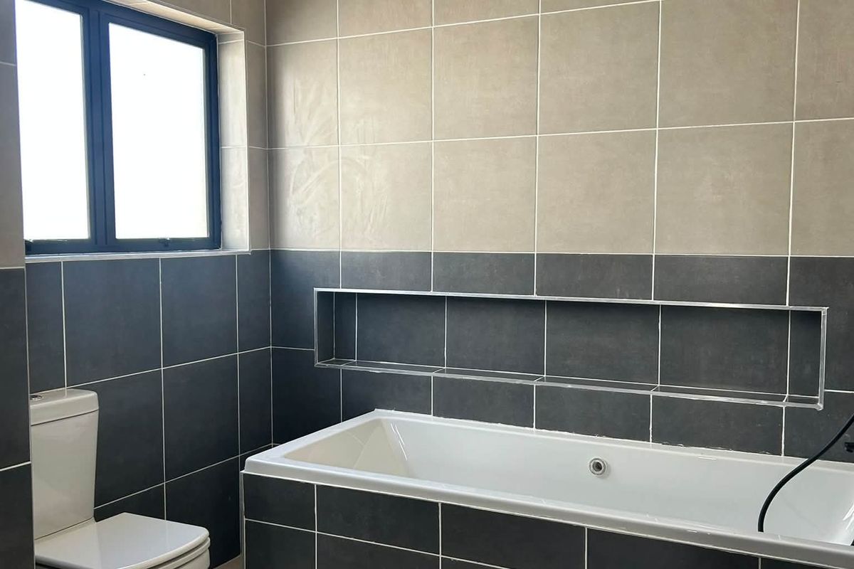 Modern bathroom featuring a built-in bathtub, a recessed wall niche for storage, and contemporary two-tone tiled walls and flooring.