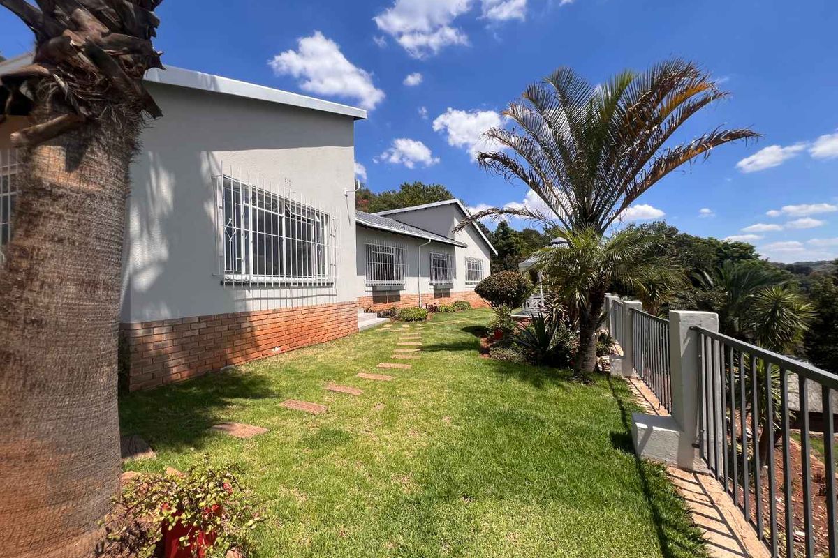 Rear exterior view of the house featuring a landscaped garden, brick foundation detailing, and security bars on the windows.