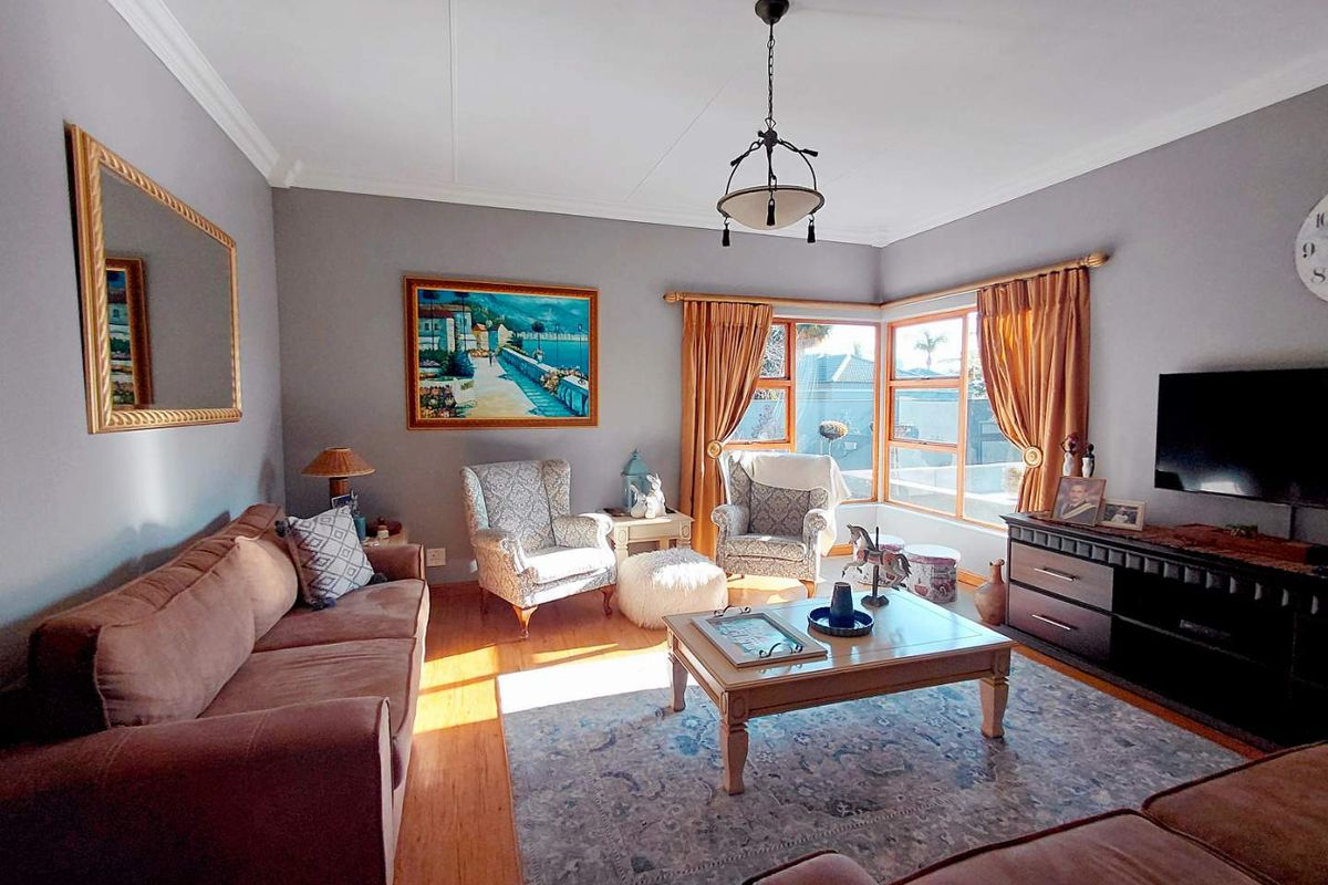 A well-maintained living room featuring laminate flooring, a bay window, and decorative cove cornicing, providing a comfortable and inviting space.