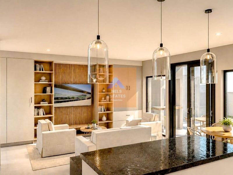 Modern open-plan living area featuring a granite kitchen island, custom built-in shelving, slatted timber wall detail, and seamless access to the outdoor patio.