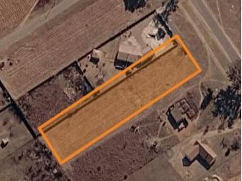 An aerial view of a rectangular vacant residential plot, highlighting the property boundaries within the surrounding neighborhood.