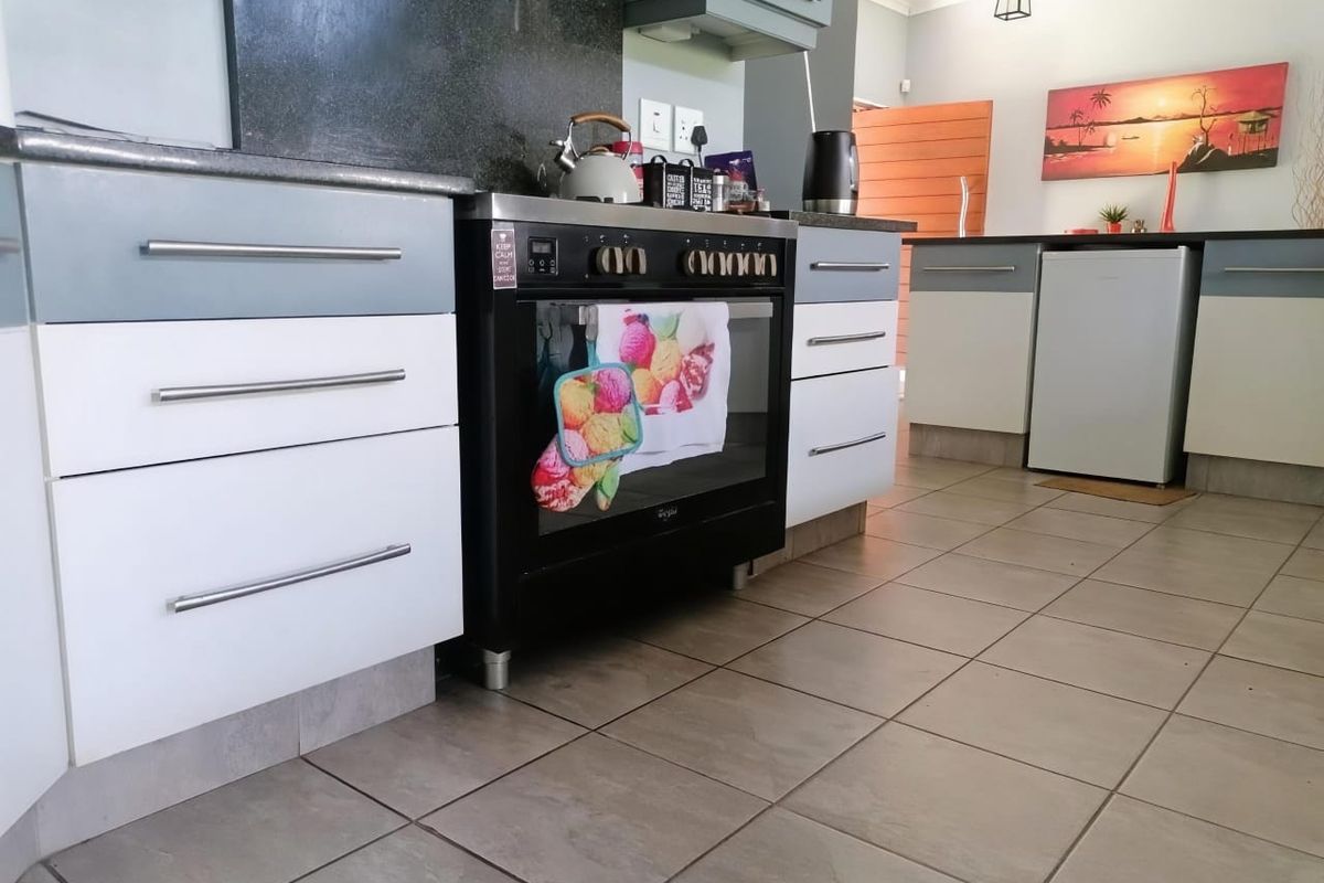 A functional kitchen featuring two-tone cabinetry, tiled flooring, and a built-in black oven with a dark stone countertop.