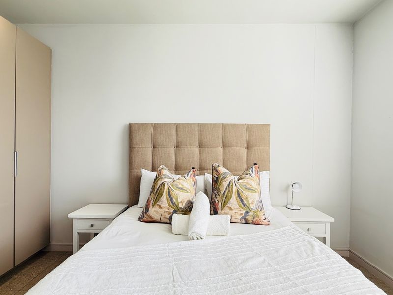 A well-maintained bedroom featuring a neutral color palette and a functional built-in wardrobe for efficient storage.