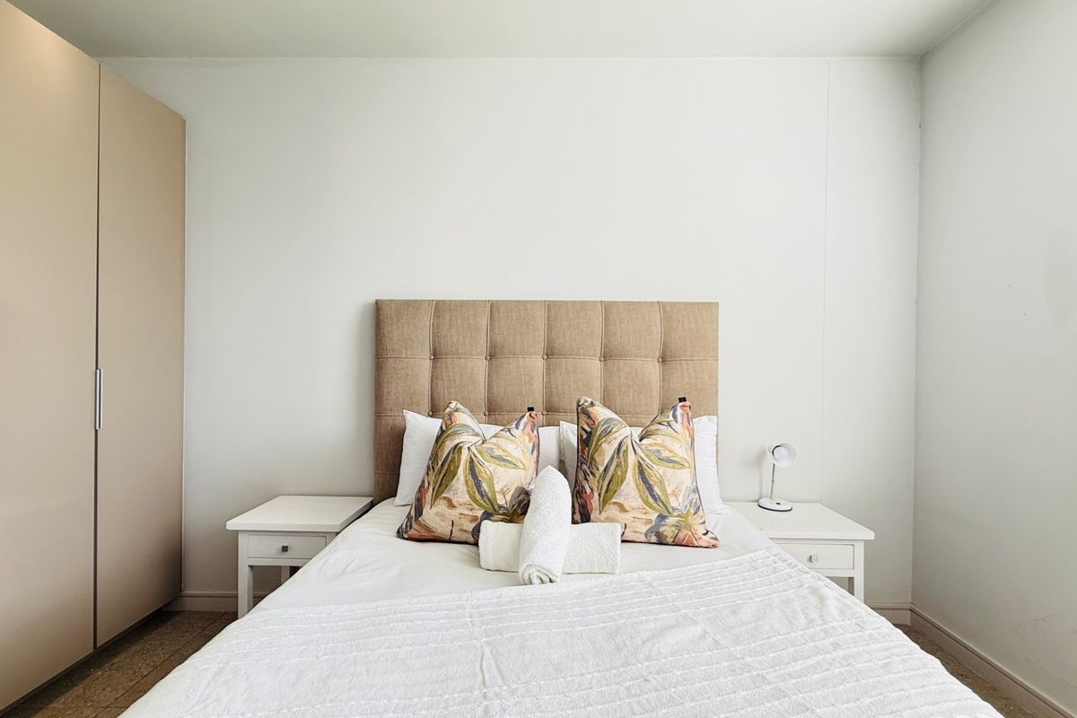 A well-maintained bedroom featuring a neutral color palette and a functional built-in wardrobe for efficient storage.
