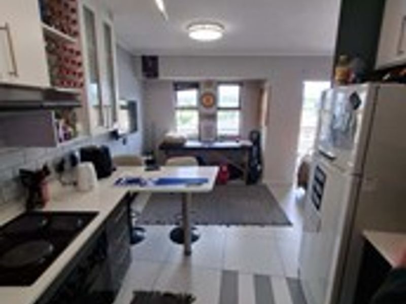 Open-plan kitchen and living area featuring tiled flooring, built-in cabinetry, and an integrated electric hob with extractor fan.