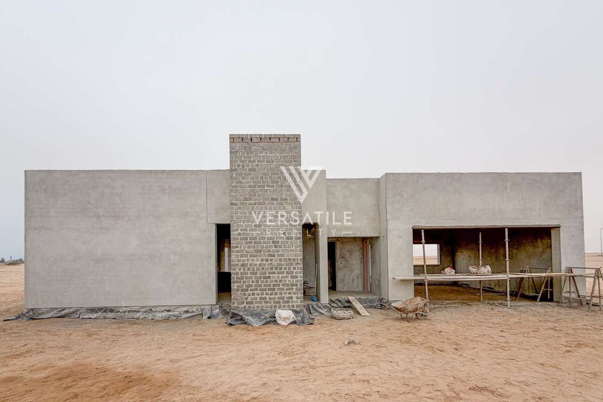 Rear view of a residential property currently under construction, featuring a cement rendered facade and an exposed brick chimney stack.