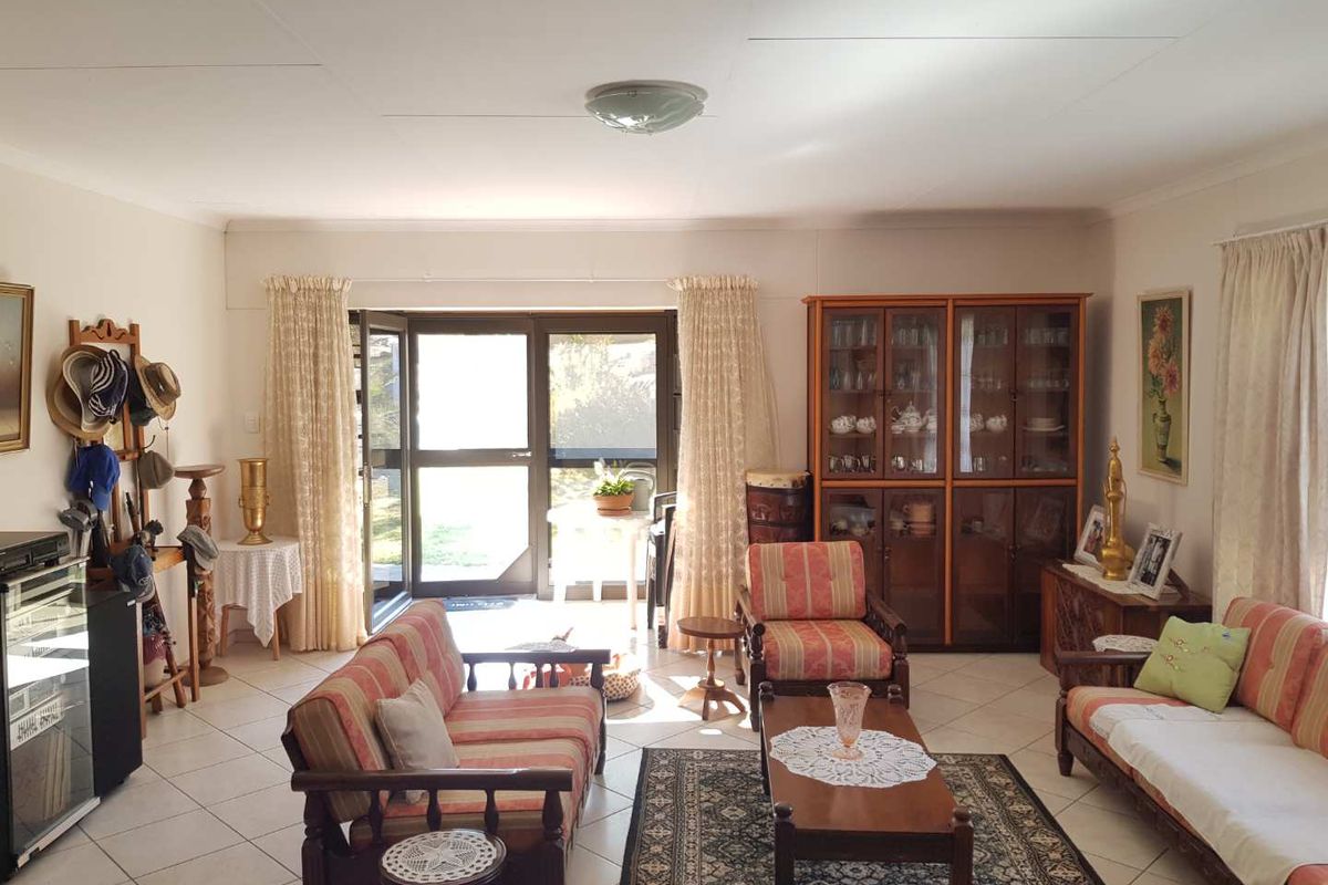 A spacious living room featuring tiled flooring and large glass sliding doors that provide direct access to the outdoor area.